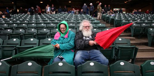 A little cold weather can't keep Santa away from a good game....Brian Sanderson and his partner Lilian unfurl their umbrellas THursday evening at Shaw Park to catch the Goldeyes and Saltdogs take to a slightly damp field in the second playoff match this week betwen the two rivals. Sanderson has been the Polo Park Santa for 22 years and is an avid baseball fan here. September 4, 2014 - (Phil Hossack / Winnipeg Free Press)