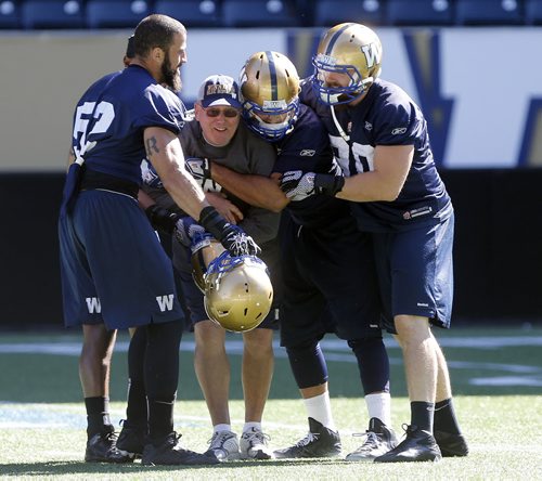 SPORTS . Blue Bomber Qb's coach Gene Dahlquist practices what he preaches , ball security  as he hold off a gang of  defensive players during practice  preparing  for game against Saskatchewan on Sunday afternoon . SEPT  5 2014 / KEN GIGLIOTTI / WINNIPEG FREE PRESS