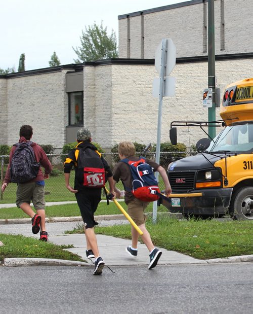 A group of boys run across Lakewood Blvd to catch their bus near Ecole Van Belleghem School Tuesday.  For story on school zone traffic signs, notifying drivers of speed limit of 30km during school hours.   See story on new school zone speed limits.  Sept 09.  2014 Ruth Bonneville / Winnipeg Free Press   Ruth Bonnevilles