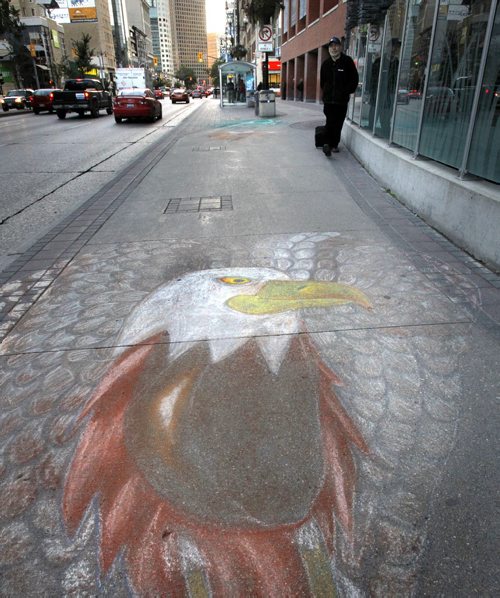 Pedestrians walk past a beautifully drawn eagle on the sidewalk along Portage Ave. by the MTS Centre Wednesday morning. The Aboriginal Peoples Choice Music Awards  will be held at the MTS Sept12 part of the 2014 Manito Ahbee Festival that  runs September 10 - 14 Wayne Glowacki/Winnipeg Free Press Sept.10 2014