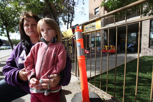 Foster mom, Chanda Bergson holds four-year-old Mya Gibson (Mya is spelt with a y) outside Family Community Centre Daycare on Sargent Ave. that has had their outdoor play area closed numerous times in past few days due to falling rocks a debris from roofers  working on the building's rooftop.  Mya attends the daycare with Bergson's foster children.  See Ashley's story.  Sept 10.  2014 Ruth Bonneville / Winnipeg Free Press   Ruth Bonnevilles
