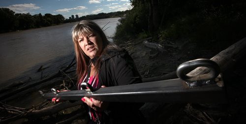 Bernadette Smith posese along the Red River Wednesday. The sister of missing woman Claudette Osborne, has created the group Drag the Red which plans to start dragging the river on Sunday looking for missing women. She's holding a bar which will be dragged across the river's bottom with hooks attached to hook possible evidence (bodies) of other missing women.  September 10, 2014 - (Phil Hossack / Winnipeg Free Press)