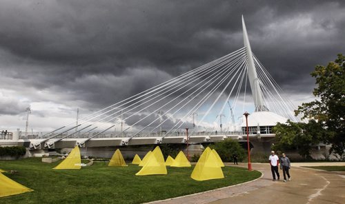 A couple walks along a path at The Forks while dark clouds move in over the Esplanade Riel Sunday afternoon.  140914 September 14, 2014 Mike Deal / Winnipeg Free Press