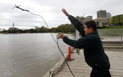Darryl Contois tosses a grappling hook off of the Alexander Docks Wednesday into the Red River in the search for missing women. see story Wayne Glowacki/Winnipeg Free Press Sept.17  2014