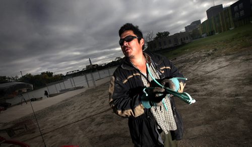 A volunteer who drove "in from the east" and didn't want to give his name looks over his shoulder at the Red River near the Alexander Docks as he fashions a grappling hook out of re-inforcing bar Wednesday. See Ashley Prest's story. September 17, 2014 - (Phil Hossack / Winnipeg Free Press)