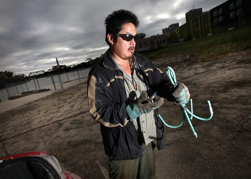 A volunteer who drove "in from the east" and didn't want to give his name looks over his shoulder at the Red River near the Alexander Docks as he fashions a grappling hook out of re-inforcing bar Wednesday. See Ashley Prest's story. September 17, 2014 - (Phil Hossack / Winnipeg Free Press)