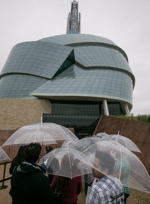 Visitors wait in the rain, with supplied umbrellas, for their preview tours at the Canadian Museum for Human Rights on Saturday. The rain kept away some of the people with reserved tickets, allowing walk-ups to gain access to the guided tour of four of 11 galleries. The rest of galleries open September 27th. 140920 - Saturday, September 20, 2014 - (Melissa Tait / Winnipeg Free Press)