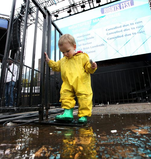 One and a half-year-old Quinn Kolisnyk plays in a puddle next to the main stage at the Forks with his green boots and yellow rain suit while waiting with his family for a band to perform on stage cancellations due to rain.  Sept 19,  2014 Ruth Bonneville / Winnipeg Free Press