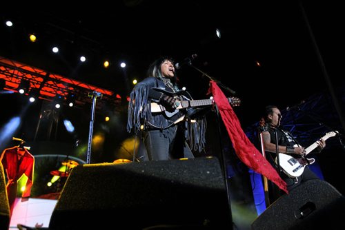 Buffy Sainte-Marie performs on the main stage during the Rights Fest at the Forks Saturday night.   A red dress which is one of many created to remember all the missing a murdered women in Manitoba is set behind her on stage as she performs.  Sept 20,  2014 Ruth Bonneville / Winnipeg Free Press