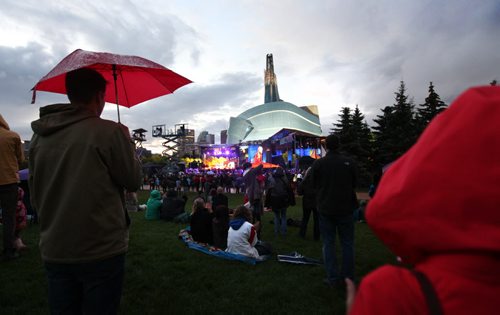 Concert goers cover themselves from the rain as they watch the performers on the main stage at the Forks during Rights Fest Saturday evening at dusk.   Sept 20,  2014 Ruth Bonneville / Winnipeg Free Press
