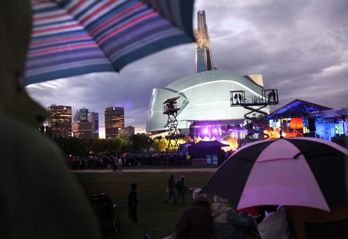 Concert goers cover themselves from the rain as they watch the performers on the main stage at the Forks during Rights Fest Saturday evening at dusk.   Sept 20,  2014 Ruth Bonneville / Winnipeg Free Press