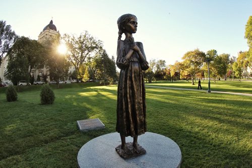 A pedestrian walks past a new monument on the grounds of the Manitoba Legislative Building Monday morning. Entitled, "Bitter Memories of Childhood" the monument commemorates the "millions of victims of the enforced starvation during the Holodomor Famine Genocide in Ukraine 1932-1933." 140922 September 22, 2014 Mike Deal / Winnipeg Free Press