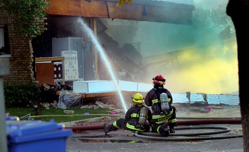 City firefighters battle a blaze at 27 Apple Lane after an explosion sent one man to hospital in critical condition. The entire north wall was blown out as seen behind the firefighters. See Ashley Prest story. September 23, 2014 - (Phil Hossack / Winnipeg Free Press)