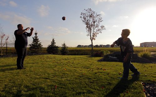 49.8 FEATURE - Wade Miller. Wade with son Branson Miller,8, chuck the football around in the back yard of their home in south Winnipeg.  BORIS MINKEVICH / WINNIPEG FREE PRESS  Sept. 24, 2014