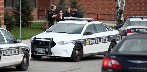 City Police officers converse in front of  Elmwood Collegiate Wednesday afternoon after a reported stabbing at or near the school. I don't know who or why the young woman is with them (Cop, Teacher,Student?) See Ashley Prest's story. October 1, 2014 - (Phil Hossack / Winnipeg Free Press)