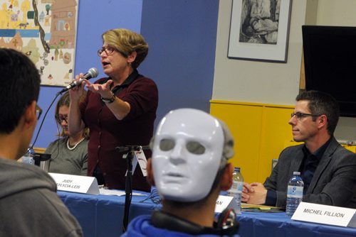 Judy Wasylycia-Leis at the mic at Mayoral forum at Rossbrook House. Brian Bowman sits and listens. A person in the crowd wears a mask on the back of his head. BORIS MINKEVICH / WINNIPEG FREE PRESS  Oct. 2, 2014