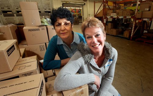 Winnipeg Harvest volunteers Nooria Rahmat (left) and Corinne Paulishyn pose in Harves't warehouse. Volunteers as  "in-home" workers hey work with struggling families coaching and supporting them so CFS doesnt need to take their kids away. Rather than nap when theyre in a home, they do crafts with the kids, wash the dishes, fold the laundry, and are a shoulder to cry on and get advice from. ¤¤Carol Sanders story. October 3, 2014 - (Phil Hossack / Winnipeg Free Press)