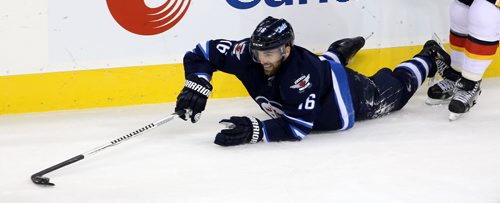 Winnipeg Jets' Andrew Ladd (16) plays the puck after being tripped up by Calgary Flames' Dennis Wideman (6) during the first period of NHL hockey action in Winnipeg, Saturday, October 4, 2014. (TREVOR HAGAN/WINNIPEG FREE PRESS)