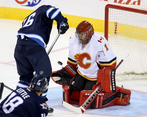 Winnipeg Jets' Andrew Ladd (16) is unable to get a bouncing puck past Calgary Flames' goaltender Jonas Hiller (1) during the first period of NHL hockey action in Winnipeg, Saturday, October 4, 2014. (TREVOR HAGAN/WINNIPEG FREE PRESS)