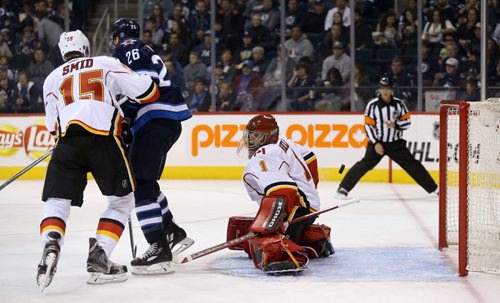 Calgary Flames' Ladislav Smid (15) tries to clear Winnipeg Jets' Blake Wheeler (26) as a shot by Jacob Trouba (8) sneaks past goaltender Jonas Hiller (1) for the Jets' second goal of the game, during the second period of preseason NHL hockey action in Winnipeg, Saturday, October 4, 2014. (TREVOR HAGAN/WINNIPEG FREE PRESS)