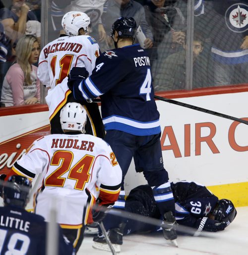 Winnipeg Jets' Tobias Enstrom (39) lays on the ice after being hit hard into the boards by Calgary Flames' Mikael Backlund (11) during the third period of preseason NHL hockey action in Winnipeg, Saturday, October 4, 2014. (TREVOR HAGAN/WINNIPEG FREE PRESS)