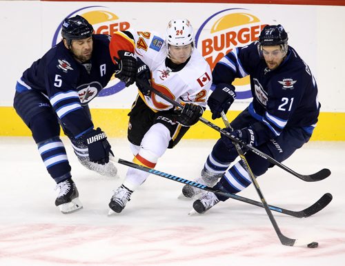 Winnipeg Jets' Mark Stuart (5) and TJ Galiardi (21) battle with Calgary Flames' Jiri Hudler (24) during the third period of preseason NHL hockey action in Winnipeg, Saturday, October 4, 2014. (TREVOR HAGAN/WINNIPEG FREE PRESS)