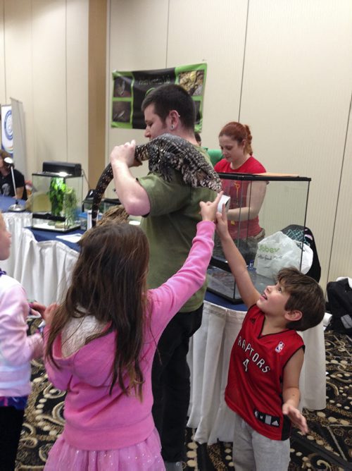 Ashley Prest / Winnipeg Free Press  Devin Bunney attracts a crowd of kids with his Argentine Black And White Tegu, a carnivorous lizard. This one really likes to eat turkey meat. Children are Anika Curtis, 9, in pink and brother Eli Curtis, 4, in red shirt. Oct. 5, 2014