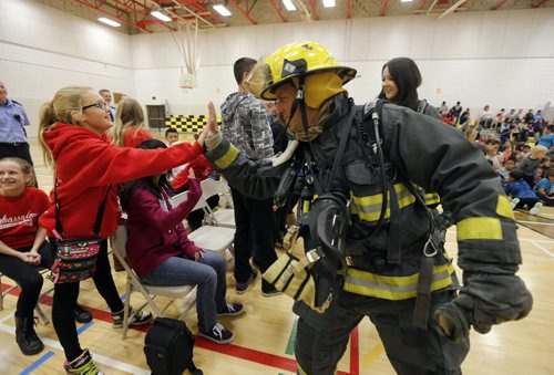 STDUP . Fire Prevention Week starts Oct 5 to11  . WPS Fire Fighter Marcel Laporte  and rear  Gr. 7 teacher Meghan McOmber  (in turnout gear ) give high fives to students at the assembly Laporte gives high five to Arizona Dejonge Gr.8.The  to  the pubic is reminded to check their smoke alarm and carbon monoxide detector batteries as well a review  home escape plans in case of fire .This years kick off was held at Bernie Wolfe School other activities during the week include WFS Fire Drill across the city schools on Friday  and Saturday  the Fire paramedic stations are open to the public for tours as well as Fire Chief for a Day event . Oct. 6 2014 / KEN GIGLIOTTI / WINNIPEG FREE PRESS
