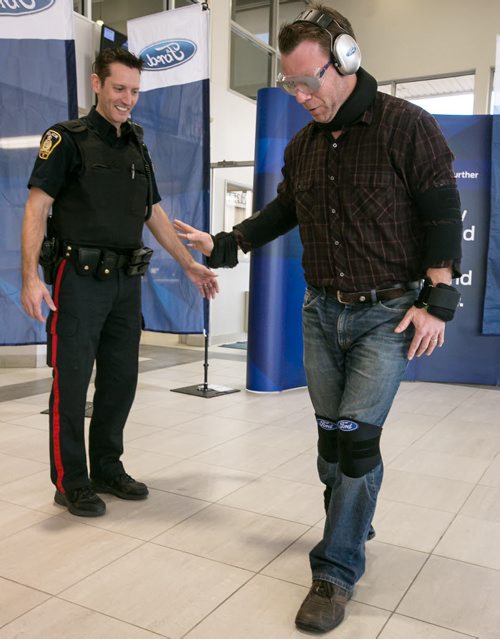Constable Stephane Fontaine of Winnipeg Police Service tests reporter Geoff Kirbyson's balance during a mock sobriety test with Kirbyson wearing weights on his arms and legs and glasses that replicate impairment. 141007 - Tuesday, October 07, 2014 - (Melissa Tait / Winnipeg Free Press)