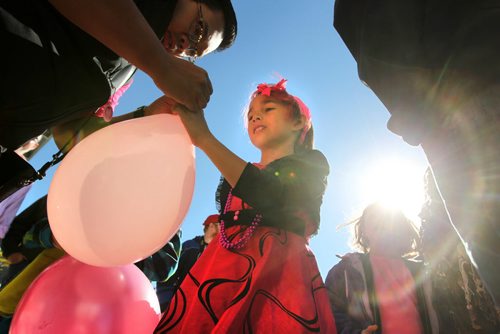 Eight-year-old Isabella Burgos - transgender (in dress) has her pink balloon tied by a family friend in Centennial Square Saturday after a rally was held in support of her wanting to live her life as a girl even though she is biologically a boy. Her parents - Izzy (mom) and Dale (dad), support her decision fully.   See Alex Paul story. Oct 11,  2014 Ruth Bonneville / Winnipeg Free Press