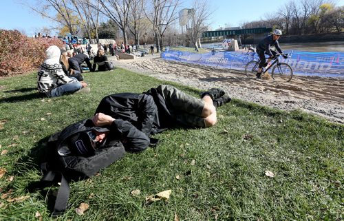A spectator grabs a quick nap as a participant in the Junior and Under 23 category at the Canadian Cyclocross Championships tests out the course around The Forks, Saturday, October 25, 2014. (TREVOR HAGAN/WINNIPEG FREE PRESS)