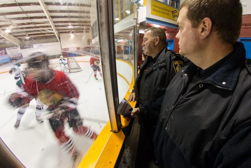 Winnipeg Police Officers Brad Sparrow (right) and Sean Donovan (centre) watch a minor league hockey game between the AAA midget Winnipeg Hawks and the Winnipeg Warriors at Notre Dame Arena Sunday morning as part of the CHECK-ing In program between the WPS and Hockey Winnipeg. 141026 - Sunday, October 26, 2014 -  (MIKE DEAL / WINNIPEG FREE PRESS)