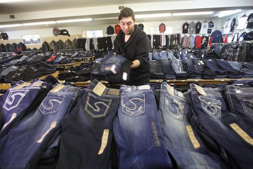 Sargent Blue Jeans located at 1136 Sargent Ave.   Mohamed El tassi,  one of the longtime employee's of the neighbourhood jean store (family member of owners), organizes the large selection of jeans on one of the long tables in store.  David Sanders feature story.   Oct 30,  2014 Ruth Bonneville / Winnipeg Free Press