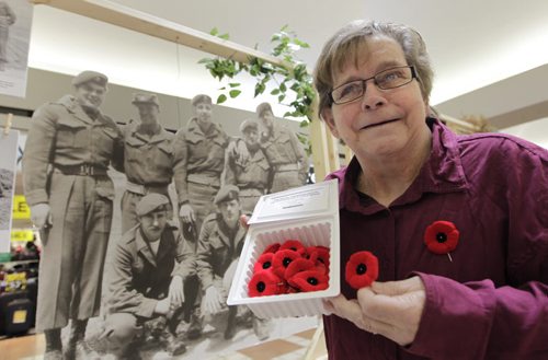 Jackie Smith, a Royal Canadian Legion member for 50 years volunteers her time at centre court in Garden City Shopping Centre selling poppies as the national annual Legion Poppy Campaign began Friday. In back is part of a photo exhibit documenting the legacy of Korean War Veterans. It is hoped that more than 18 million poppies will be worn by Canadians.  Wayne Glowacki/Winnipeg Free Press Oct.31   2014