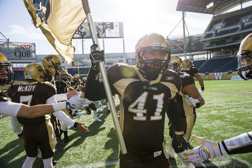 141101 Winnipeg - DAVID LIPNOWSKI / WINNIPEG FREE PRESS  The University of Manitoba Bisons Lauren Kroeker (#41) carries the flag before their game against the Calgary Dinos at Investors Group Field Saturday November 1, 2014. The Bisons beat the Dinos 50-31 which secures them a playoff spot.