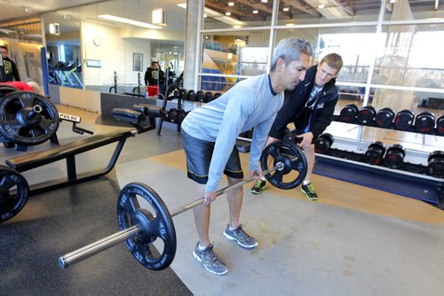 Wellness Centre. Howie Eugenio performs  hip hinge/straight leg deadlift while Karson Prost spots/coaches him. For this week's 49.8 section. BORIS MINKEVICH / WINNIPEG FREE PRESS November 13, 2014