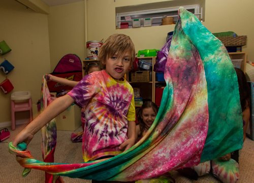Patrick Johnston, 6, waves a tie-died sheet while his sisters, Norah, 8 (right) and Isabel, 3 (behind Patrick) watch. Their mother, Mandy Johnston (right) is the owner of a home-based biz called Over the Rainbow. Mandy is a tie-dye artist - she has a line of tie-dye babywear, plus she dyes pretty much anything - diapers, tablecloths, dresses - people bring her. 141113 - Thursday, November 13, 2014 -  (MIKE DEAL / WINNIPEG FREE PRESS)