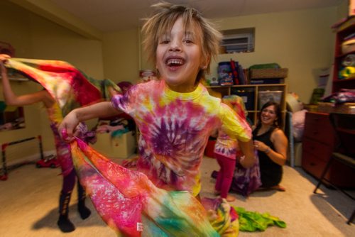 Patrick Johnston, 6, waves a tie-died sheet while his sisters, Norah, 8 (right) and Isabel, 3 (behind Patrick) dance around their mother, Mandy Johnston (right) who is the owner of a home-based biz called Over the Rainbow. Mandy is a tie-dye artist - she has a line of tie-dye babywear, plus she dyes pretty much anything - diapers, tablecloths, dresses - people bring her. 141113 - Thursday, November 13, 2014 -  (MIKE DEAL / WINNIPEG FREE PRESS)