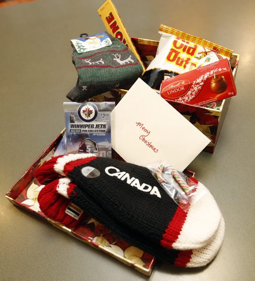 STDUP .  Contents of the shoe box size Christmas  boxes  include  socks , mits , candy , Wpg Jets pins  and potato chips. Soldiers Christmas Boxes were  put together by seniors of the Sturgeon Creek Retirement Residence  for deployed Canadian service personnel  on active duty around the world . LtoR Canadian Forces  Captain Ken Mick receives boxes made up by seniors including (back rear) Al Chaisson , William Johnston (red sweater) Rona Goldberg event planner , and Gerard Schmitz  . There are 95 boxes for local servicemen from 17 Wing and more will be made up for all deployed soldiers by the 23 Retirement Homes partners across Canada . Late last week our Event Planner, Ronna Goldberg, received a phone call from Canadian Forces Captain Mick with an interesting ask if we pooled the resources at our 24 retirement residences across Canada would we be able to put together 600 shoe box size gift packages to be sent to soldiers deployed overseas? (including 95 Manitobans) Well I am proud to let you know that we did it! Tomorrow at 10:00am at our Sturgeon Creek I Retirement Residence Ronna will be presenting Captain Mick with gift boxes containing special reminders of home to be given to our soldiers at Christmas. (Everything from 200 pins donated by the Winnipeg Jets to an individual letter of thanks for an 11 year old Winnipeg grade 6 student to chocolate bars).
 .NOV. 14 2014 / KEN GIGLIOTTI / WINNIPEG FREE PRESS