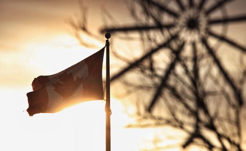 The sun lights up a Canadian flag on Main Street briefly as cold, brisk winds bring down the temperature that is hovering around -10C.  141116 November 16, 2014 Mike Deal / Winnipeg Free Press