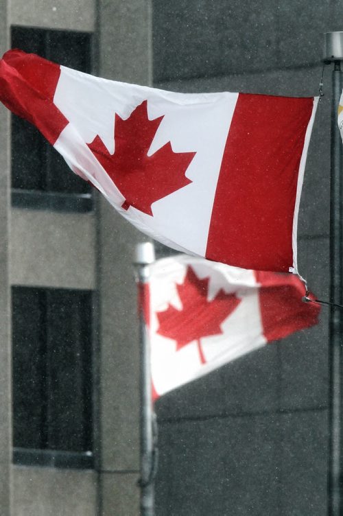 Flags fly in all directions from strong gusts of wind at Portage Avenue and Main Street Sunday afternoon.  141116 November 16, 2014 Mike Deal / Winnipeg Free Press