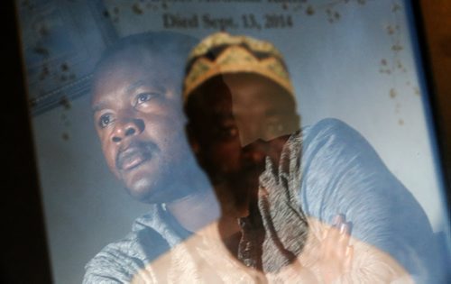 Reflecting off a photograph of his recently deceased father, Mohamed, is a Winnipeg man who lost 13 family members to ebola in Sierra Leone, Sunday, November 16, 2014. (TREVOR HAGAN/WINNIPEG FREE PRESS) - carol sanders story