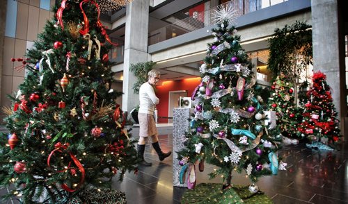 A pedestrian checks out some of the brightly decorated Christmas trees that are a part of The Festival of Trees and Lights, in the lobby of the Manitoba Hydro building. The festival is a fundraiser for the Children's Rehabilitation Foundation and Gardens Manitoba.  141118 November 18, 2014 Mike Deal / Winnipeg Free Press