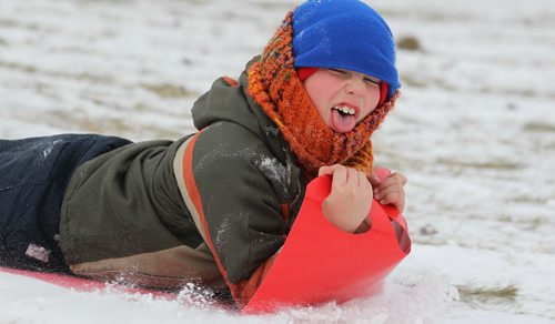 Nine year old Scott Wilkinson reacts to snow in his face as he slides with his familyTuesday at "River Hill" which runs under the train tracks along Wellington Cresent.   Standup photo  Nov 18,  2014 Ruth Bonneville / Winnipeg Free Press