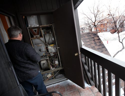 A furnace service rep puzzles at Valerie Ferguson's deck mounted furnace Tuesday. SHe didn't want to be photographed and the service rep didn't weant to be id'd but was OK with a photo from behind. See Alex Paul's story. November 18, 2014 - (Phil Hossack / Winnipeg Free Press)