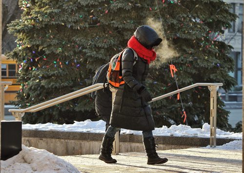 A bundled up pedestrian walks by the Christmas tree outside City Hall early Thursday morning as temperatures hovered around -25C.  141127 November 27, 2014 Mike Deal / Winnipeg Free Press