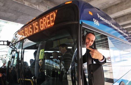NDP Minister of Jobs and Industry, Kevin Chief, points to the sign stating the bus is environmentally friendly after the announcement that battery electric transit buses are going to be deployed at the James Richardson Armstrong Airport for Winnipeg Transit. 141127 November 27, 2014 Mike Deal / Winnipeg Free Press