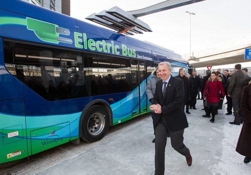 Barry Rempel President and CEO of the Winnipeg James Armstrong Richardson Airport walks by the new electric bus. The roof mounted pantograph is deployed to recharge batteries while passengers disembark when the electric bus pulled into the charging station after the announcement that battery electric transit buses are going to be deployed at the James Armstrong Richardson Airport for a Winnipeg Transit route. It recharges it's battery in about ten minutes, enough to get it through its two-hour route.  141127 - Thursday, November 27, 2014 -  (MIKE DEAL / WINNIPEG FREE PRESS)