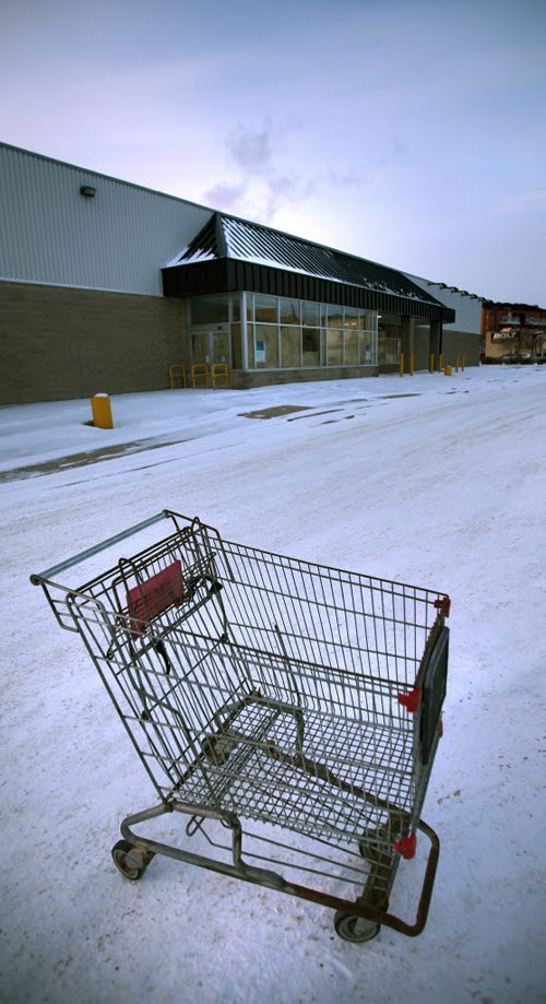 An abandoned shopping cart sits in the empty parking lot of an abandoned "Extra Foods" on Notre Dame. Residents in two older Winnipeg neighbourhoods are getting back something they lost two years ago -- a discount grocery store for their area. Loblaws has confirmed it will be converting its former Extra Foods stores on Notre Dame and Main Steet  into No Frills grocery stores. Both new franchises to open sometime in the first half of 2015. (McNeill. 12 Ours alone) December 2, 2014 - (Phil Hossack / Winnipeg Free Press)