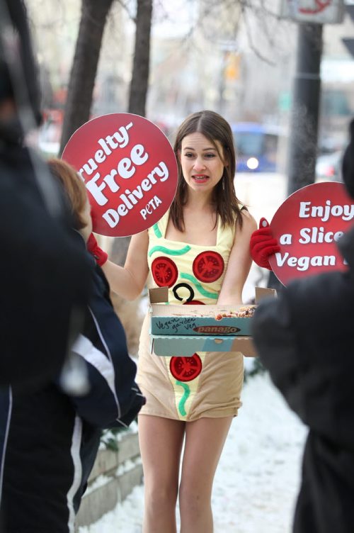 Emily Lavender sells the virtues of being vegan to a passer-by by handing out free vegan pizza in only a short dress in front of Portage Place Wednesday.  A warmly dressed older women chastises them for using their bodies to sell their ideas but  concerns goes mostly unheard.  See Bartley Kives story.  Dec 03,  2014 Ruth Bonneville / Winnipeg Free Press